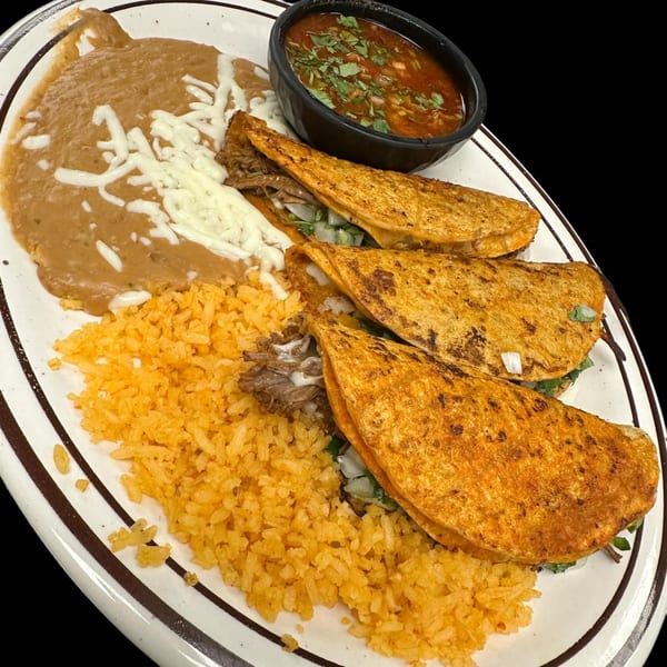 Three birria tacos with rice, refried beans, and a side of consommé on a white plate.