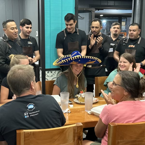 Restaurant staff celebrating a customer's birthday with a sombrero and dessert at La Cantina Mexican.