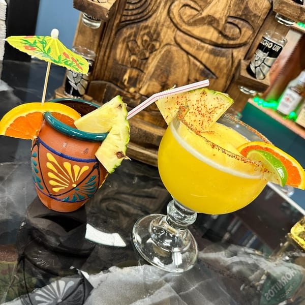 Two vibrant Mexican drinks, one in a clay mug with an umbrella, the other a margarita with fruit.