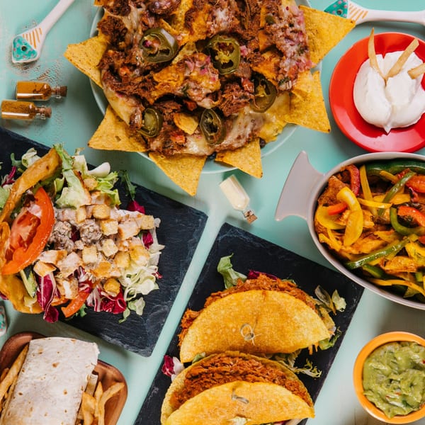 A vibrant spread of La Cantina Mexican dishes, including nachos, tacos, fajitas, salad, and a burrito.